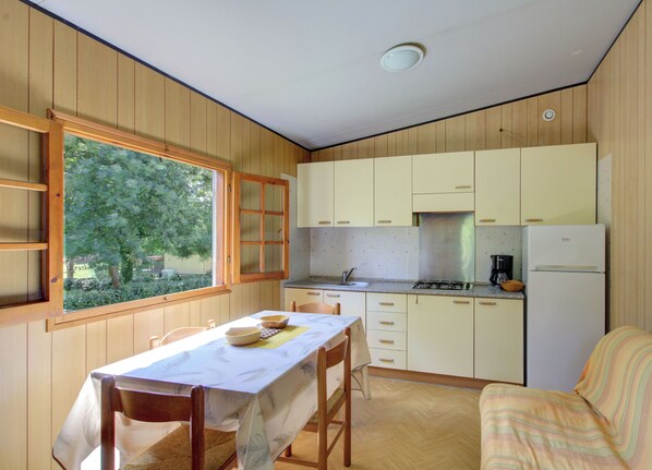 Une cuisine compacte avec des meubles en bois, une table à manger et une vue sur la verdure environnante.