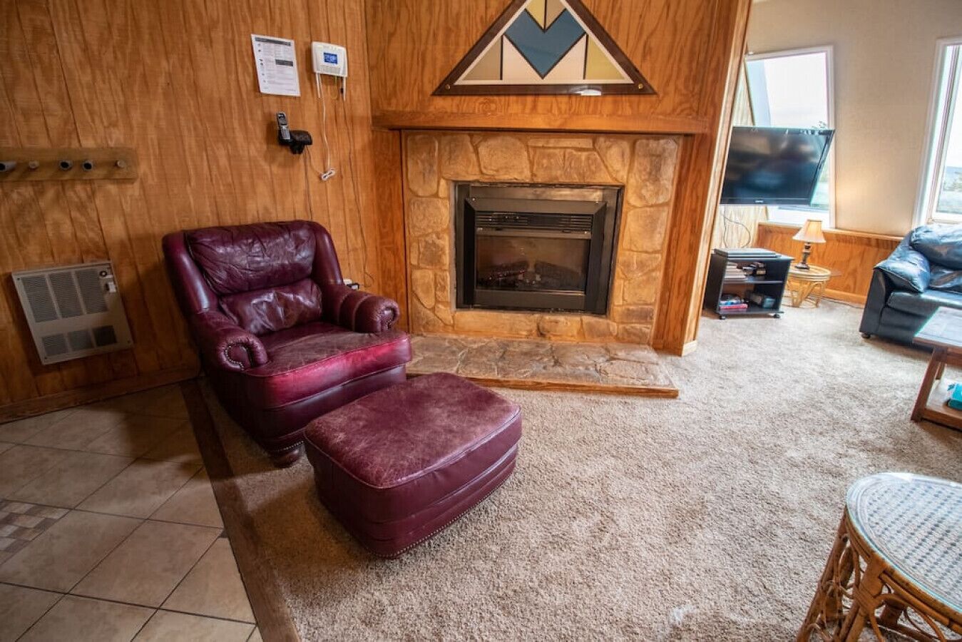 A cozy living room with a stone fireplace, a leather armchair, and a television.