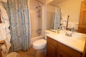 A bathroom with a shower, toilet, and vanity with a mirror.