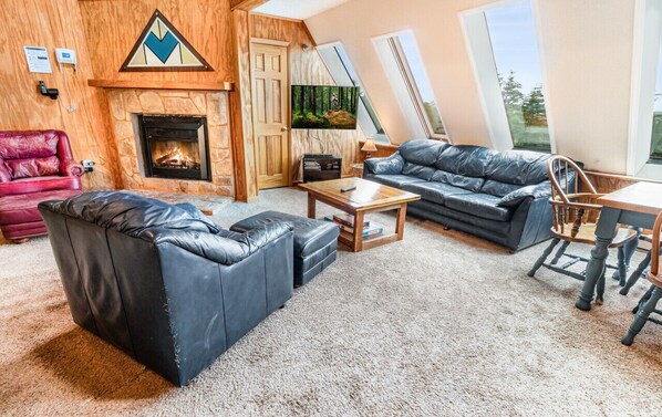 A cozy living room with a fireplace, leather sofas, a coffee table, and a dining table.