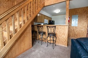 Una cocina con armarios de madera, una barra con taburetes y una escalera.