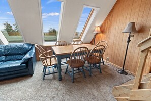 A room with a dining table and chairs, a blue sofa, and a lamp.