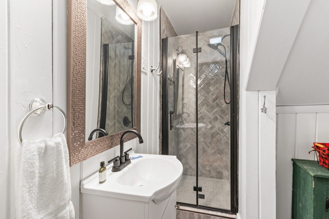 A bathroom with a glass-enclosed shower, a white sink, and a towel rack.