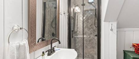 A bathroom with a glass-enclosed shower, a white sink, and a towel rack.