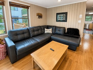 Ein Wohnzimmer mit einer Eckcouch, einem Couchtisch aus Holz und einer Wanddekoration mit Bärenmotiv.