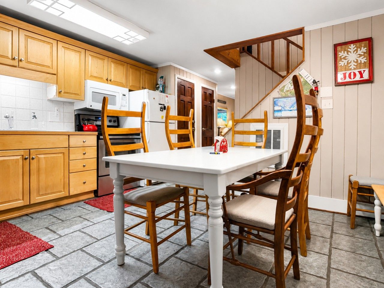 A kitchen with wooden cabinets, a white table, and chairs.