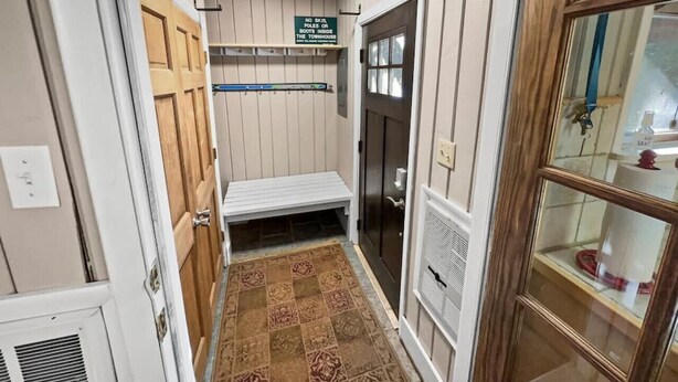 A narrow hallway with a wooden bench, a sign prohibiting skis and snow boots, and a glass door leading to a bathroom. - Townhome Near Slopes Village Gated Parking Wi-Fi (Snowshoe)