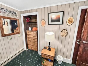 Una habitación con un aparador de madera, una lámpara, un cuadro enmarcado y una puerta con un cartel encima.
