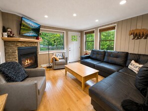 Una sala de estar con chimenea, un sofá, una mesa de centro y un televisor montado en la pared.