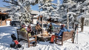 A group of people sitting around a fire pit in a snowy outdoor setting with wooden benches and snow-covered trees. - Townhome Near Slopes Village Gated Parking Wi-Fi (Snowshoe)