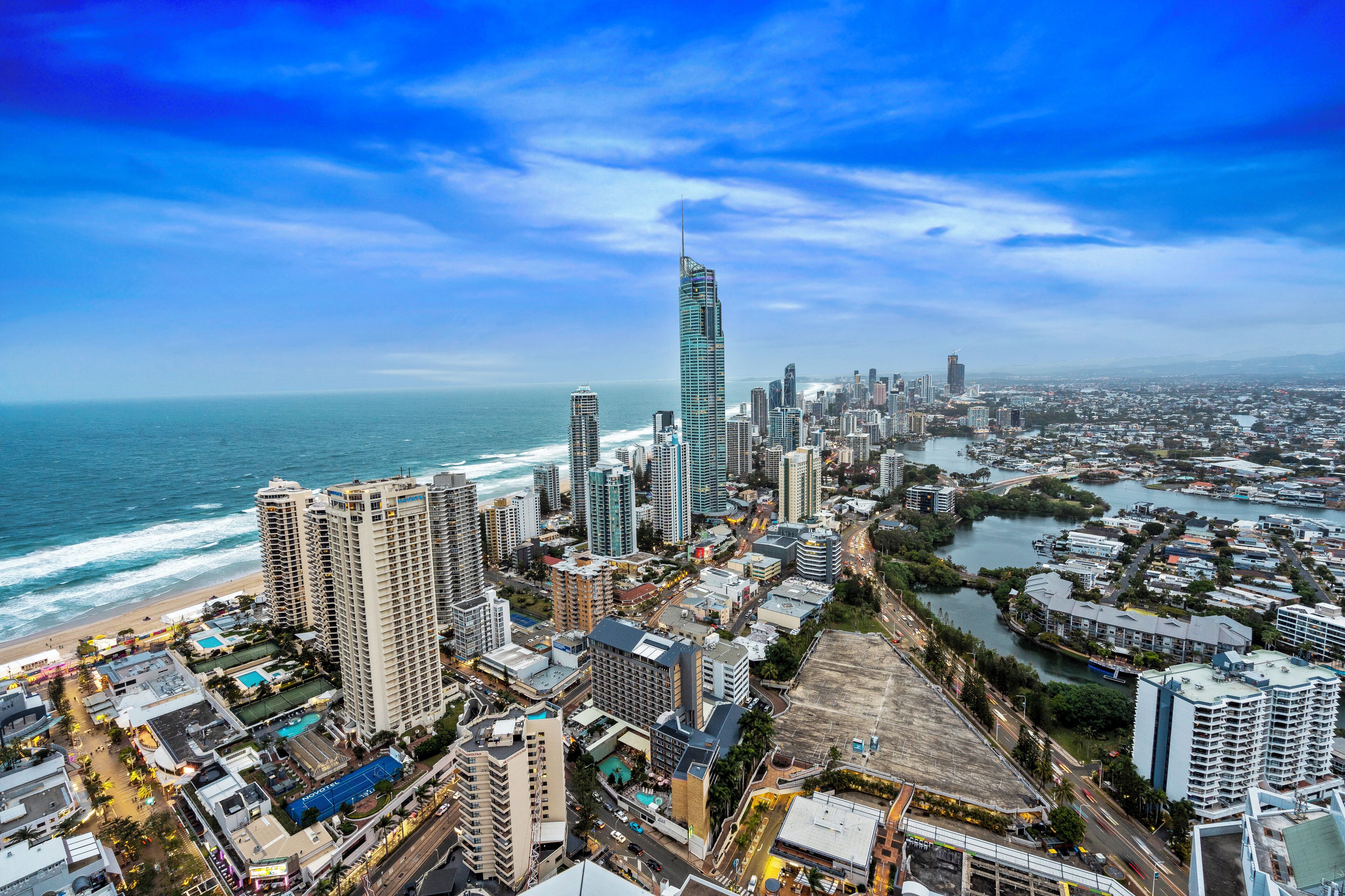Un paisaje urbano costero con edificios altos, un rascacielos destacado y una playa.