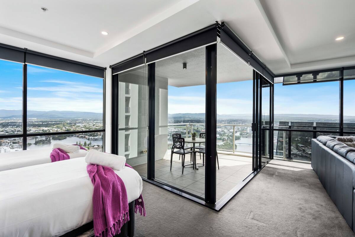 Una habitación de hotel moderna con balcón, ventanas amplias y vistas a la ciudad.