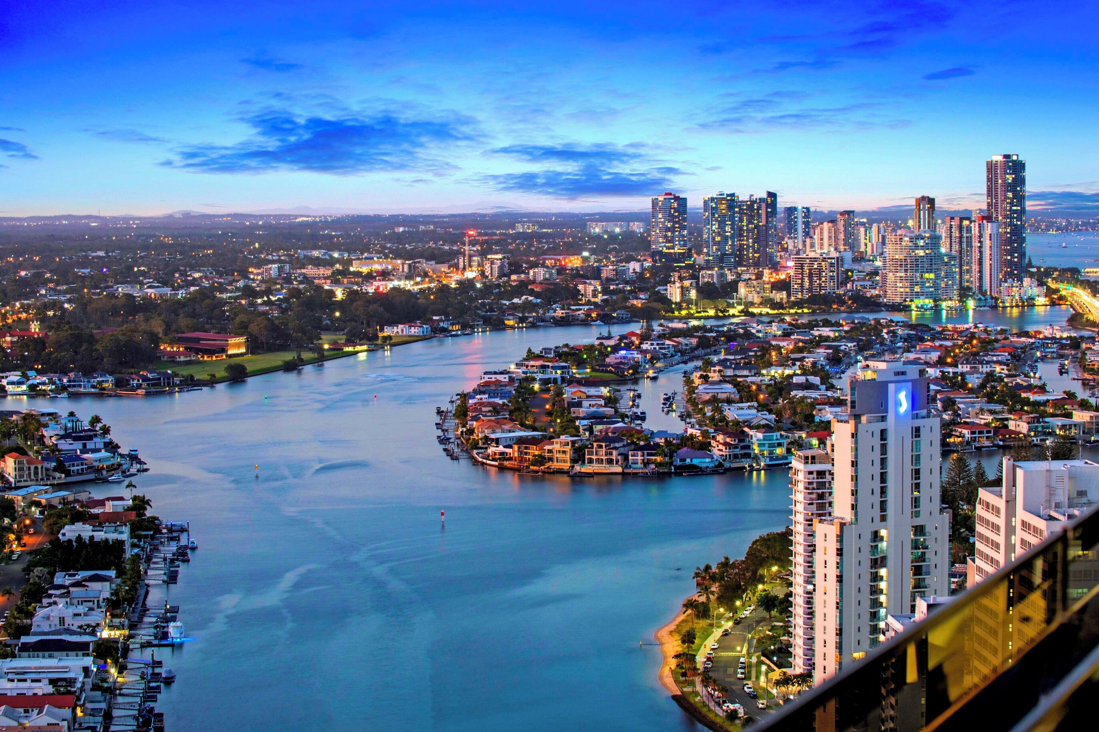 A coastal cityscape with high-rise buildings, a marina, and a river.