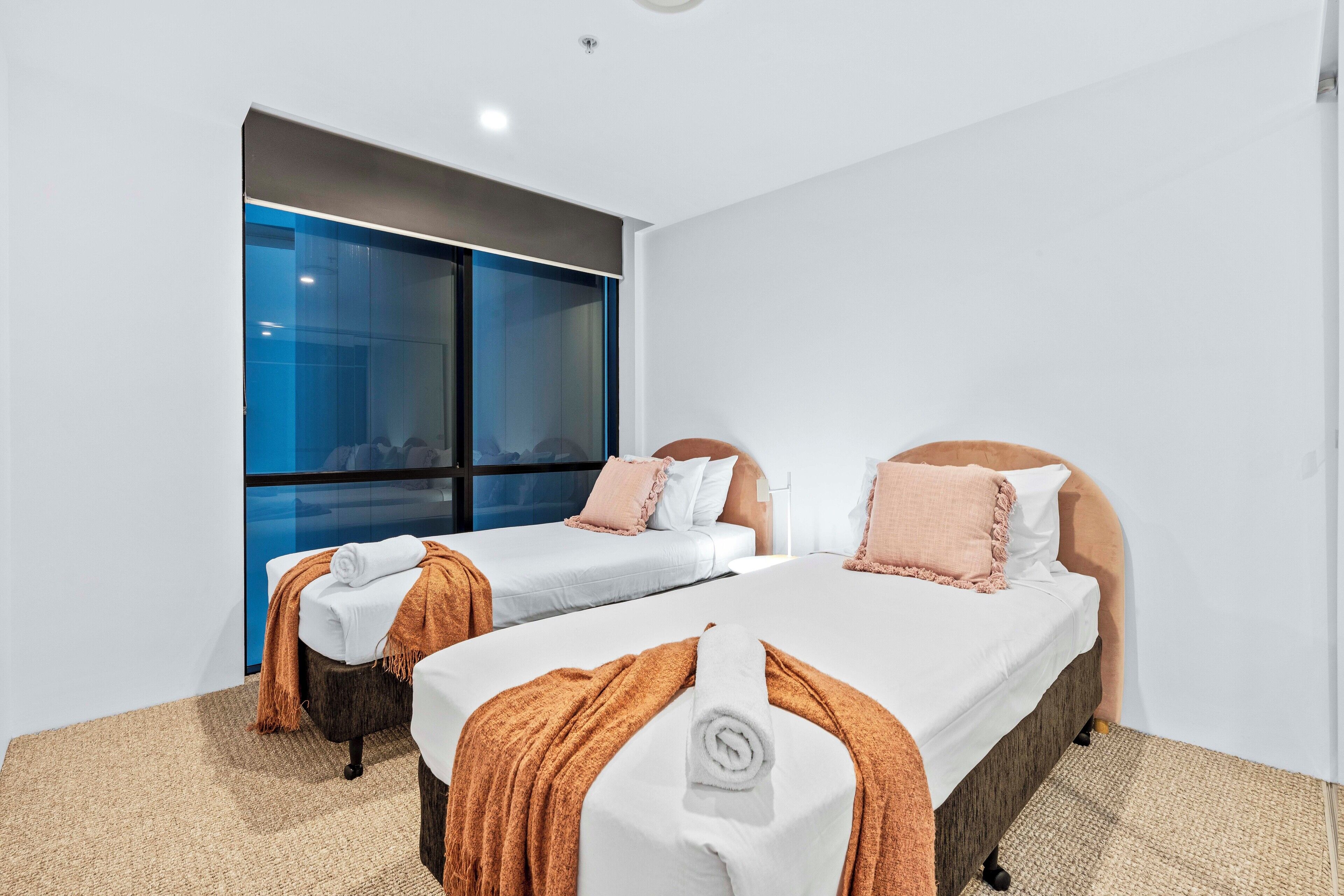 Una habitación de hotel con dos camas, un ventanal grande y vistas a la ciudad.