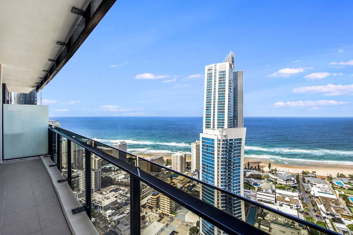 Un balcón con vista al océano y un edificio alto.