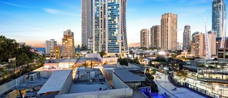 A cityscape with high-rise buildings, a rooftop pool area, and a clear sky.
