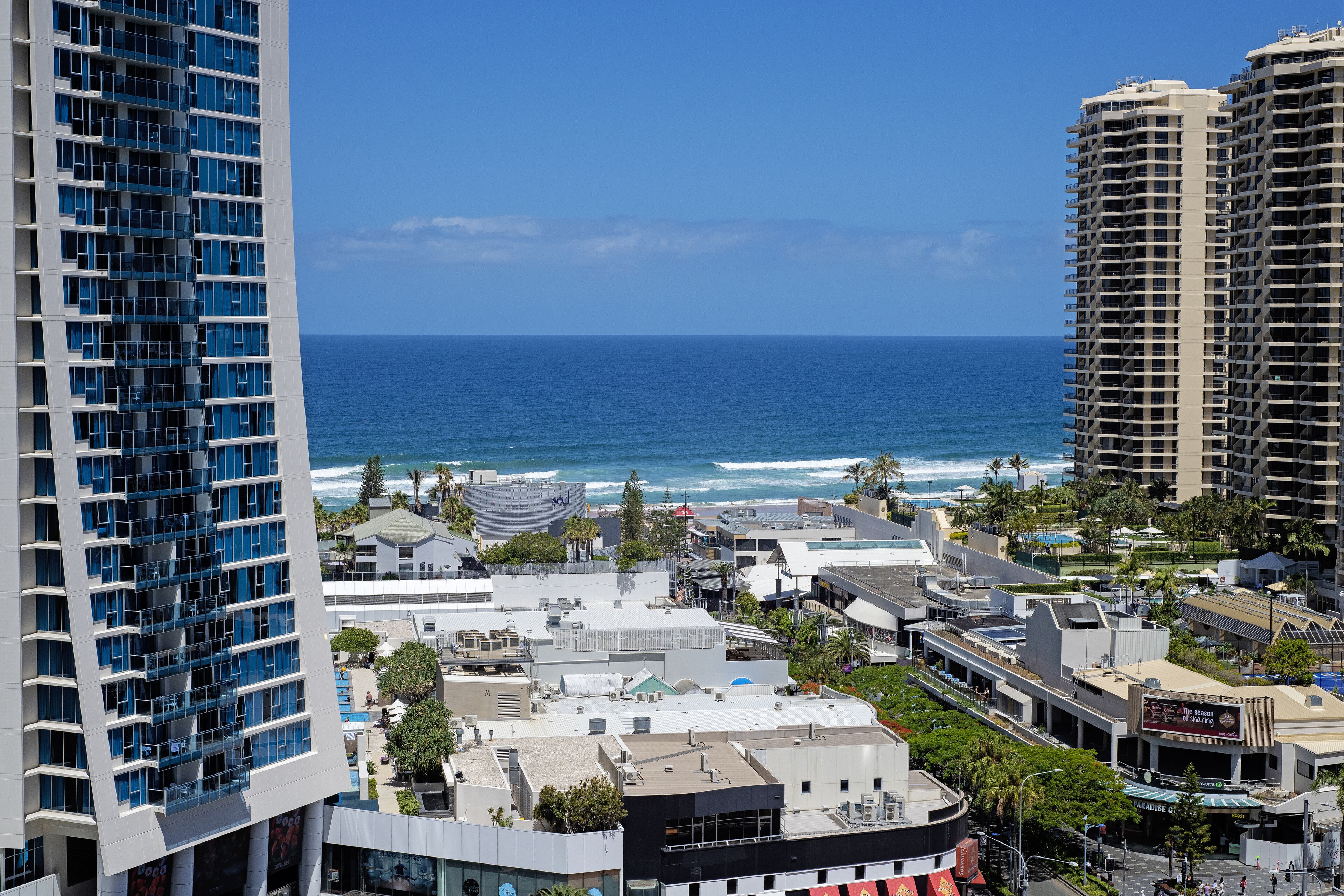 Un hotel moderno con vista sull'oceano, dotato di diversi balconi e una terrazza panoramica.