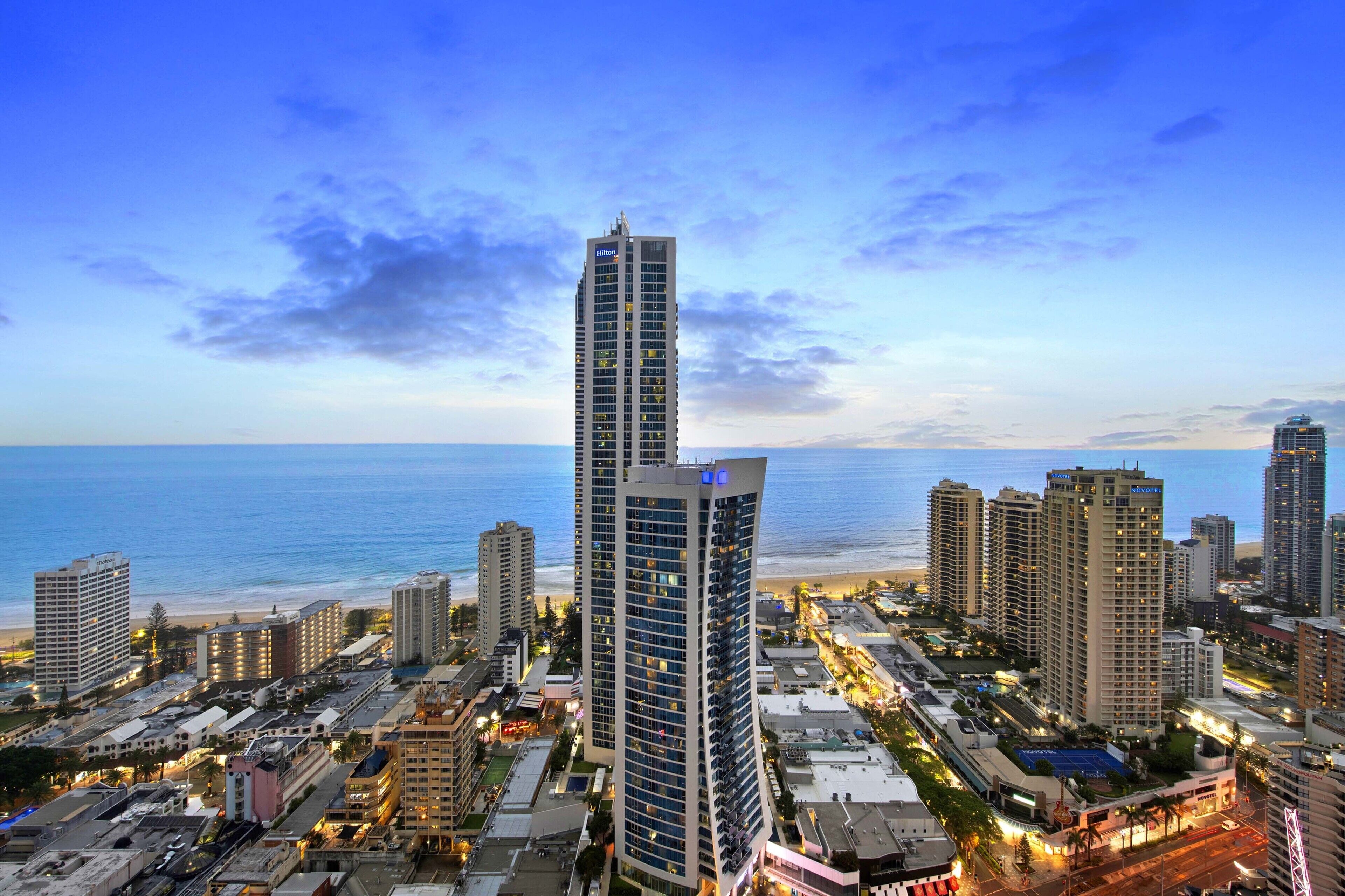 A high-rise hotel with multiple floors, located near a beach with a view of the ocean.