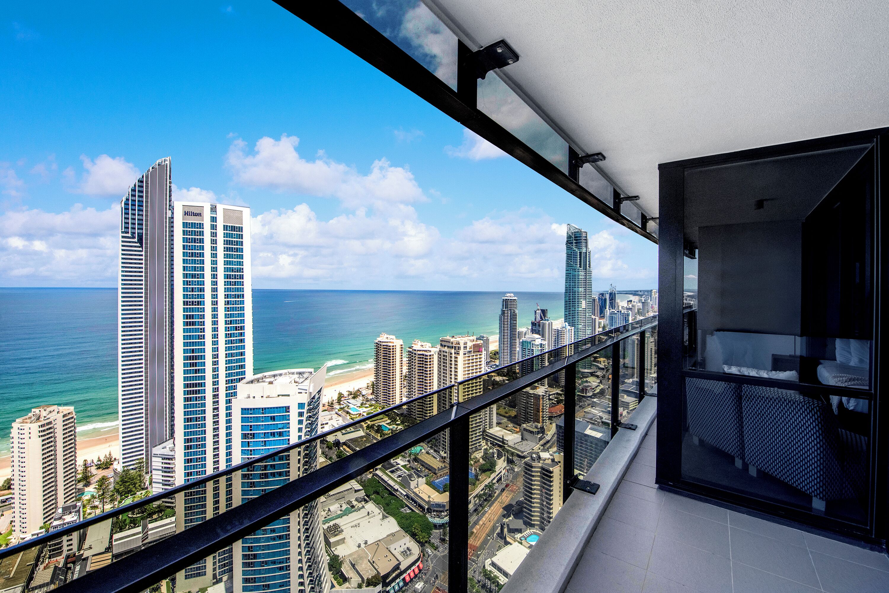 Ein Hotelzimmer im Hochhaus mit Balkon und Blick auf Stadt und Meer.
