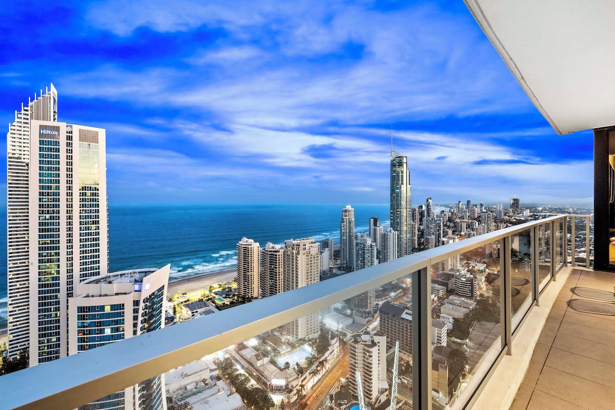 Un hotel moderno de gran altura con balcón que ofrece vistas a una ciudad costera y al océano.