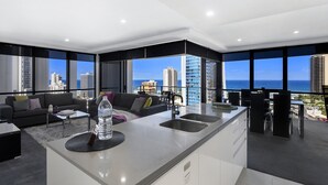 Un apartamento moderno con isla de cocina, zona de comedor y amplios ventanales con vista a la ciudad.