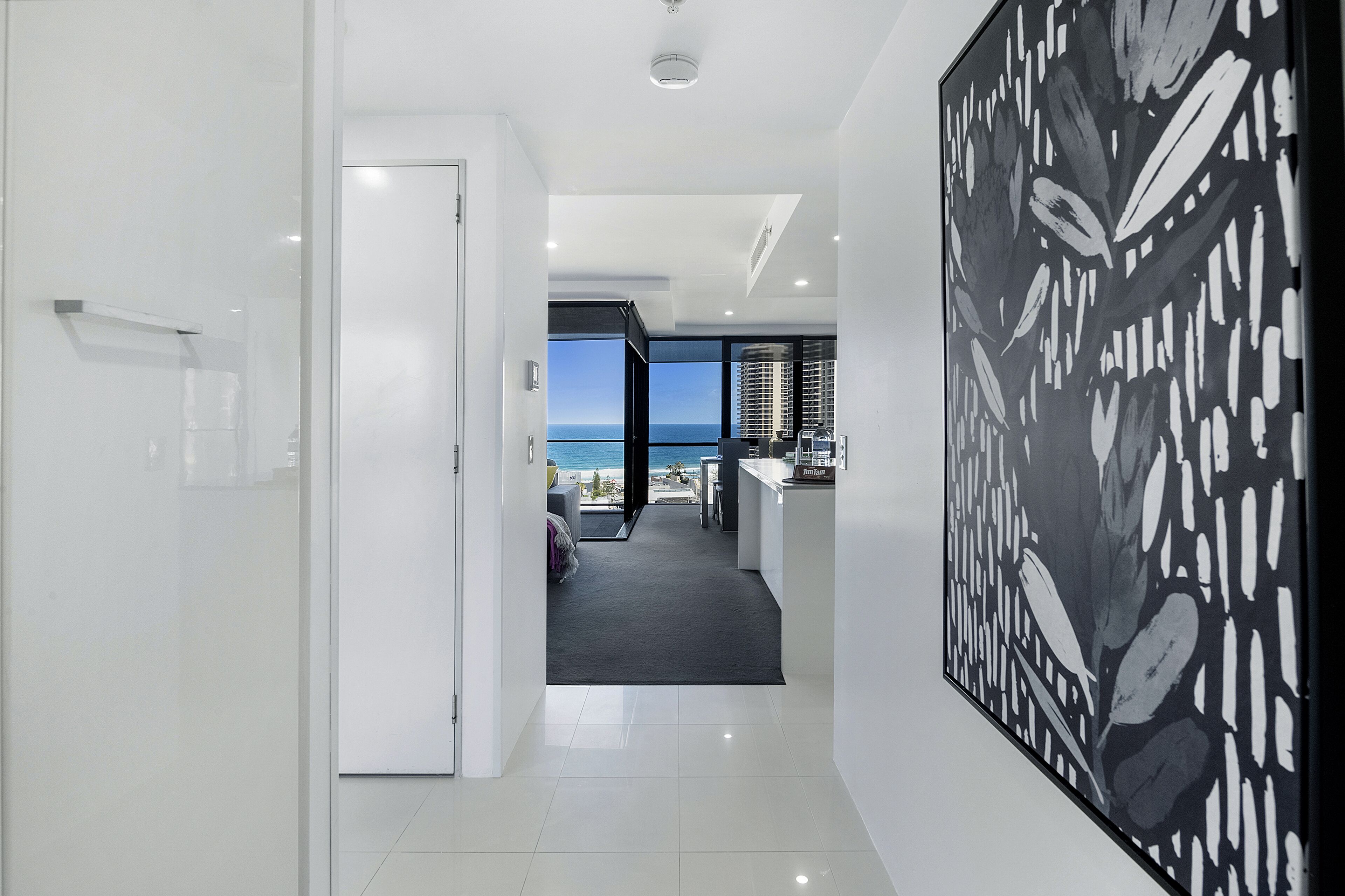 A modern hallway with a view to the sea, a large abstract painting, and a minimalist design.