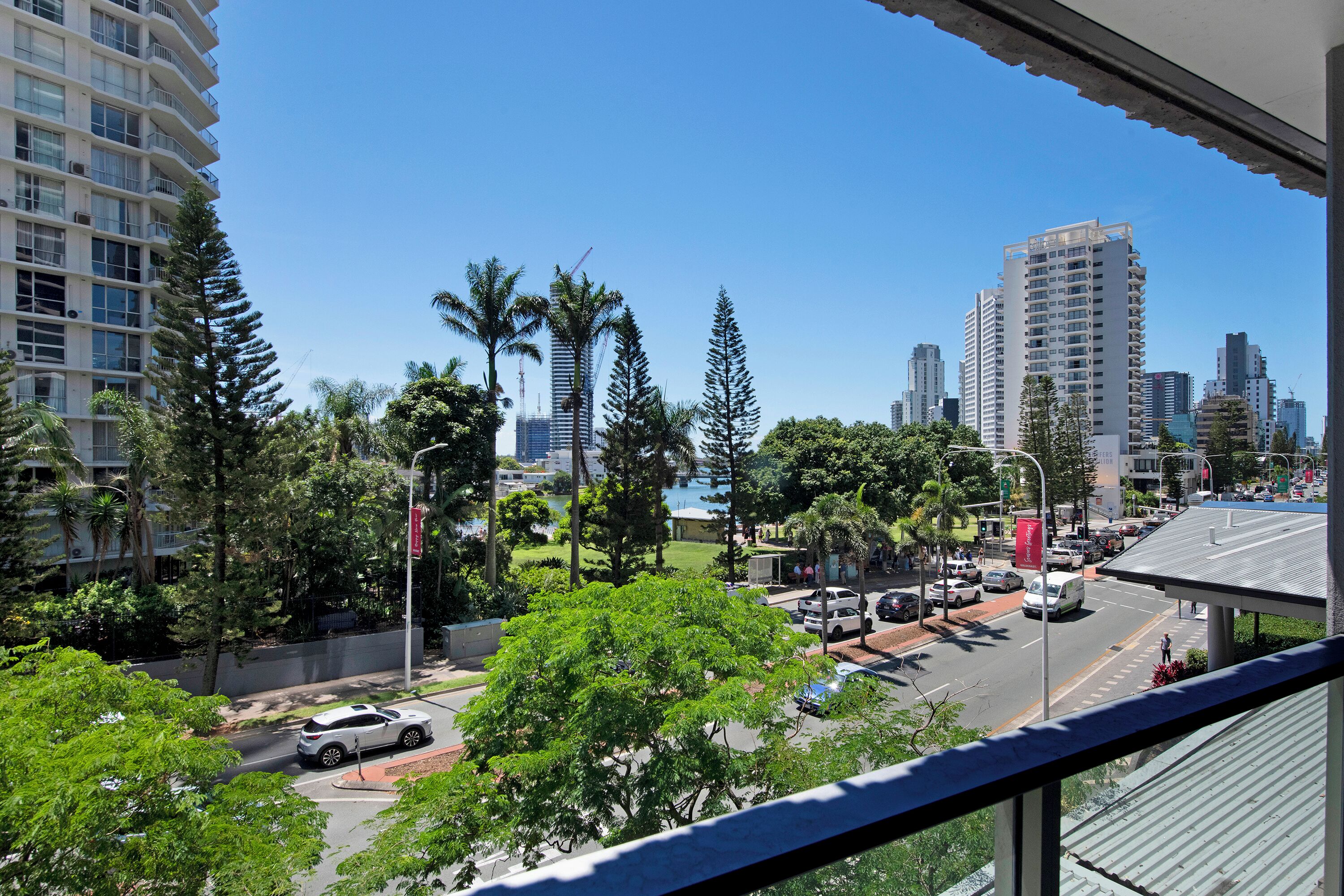 A cityscape with tall buildings, a busy street, and lush greenery.