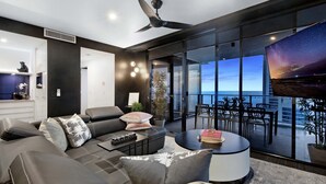 Un moderno salón con sofá, mesa de centro y balcón con vistas al horizonte de la ciudad.