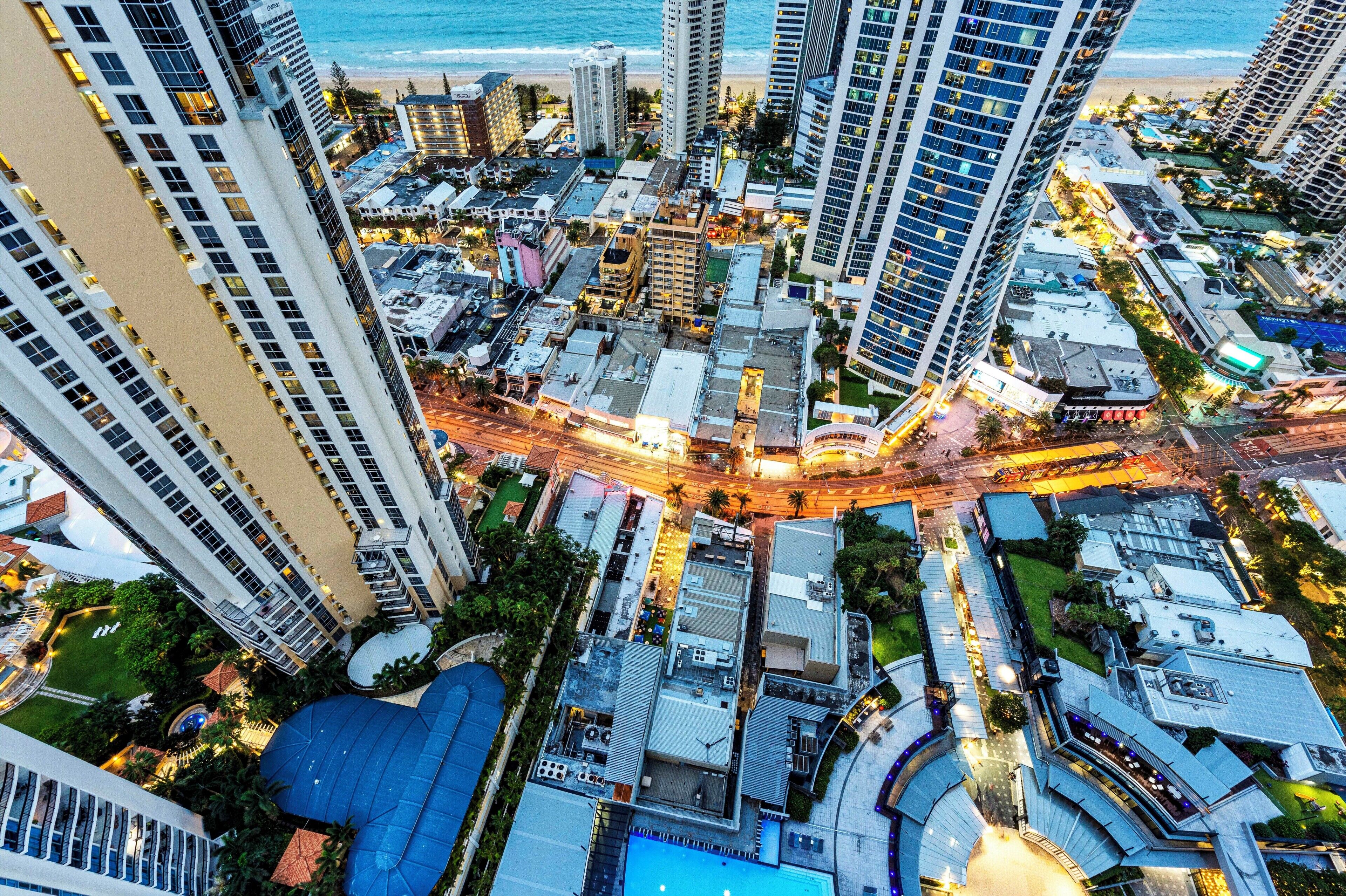An aerial view of a coastal urban area with high-rise buildings, a central intersection, and a beach in the background.