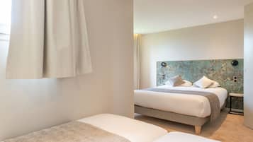 Un dormitorio moderno con una cama grande, una cama más pequeña y una mesita de noche.