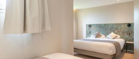 Un dormitorio moderno con una cama grande, una cama más pequeña y una mesita de noche.