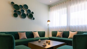 A modern living room with a green sofa set, a wooden coffee table, and a decorative wall piece. - The Originals Boutique, Hôtel Porte de Dieppe (Saint-Aubin-sur-Scie)