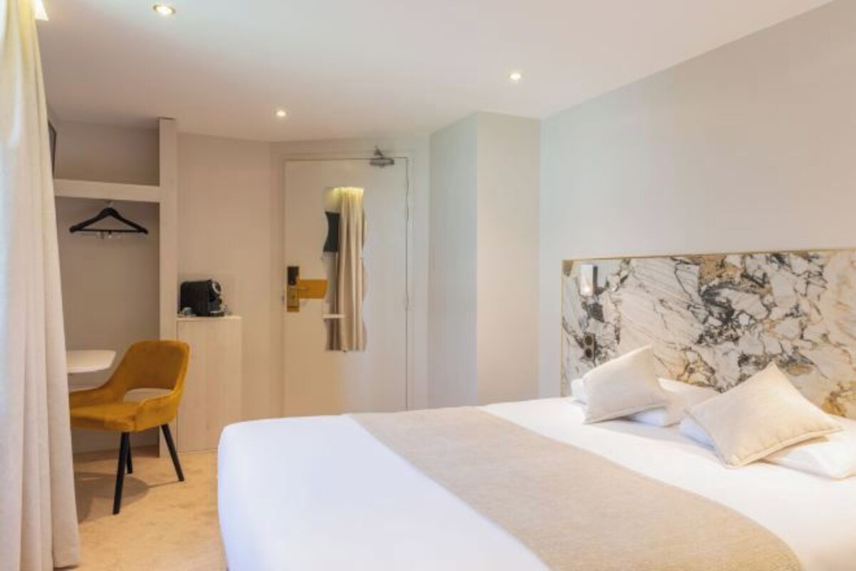 A modern hotel room with a large bed, a desk, and a chair.