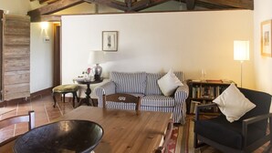 Uma sala de estar acolhedora com uma mesa de madeira, sofá riscado e uma estante de livros.
