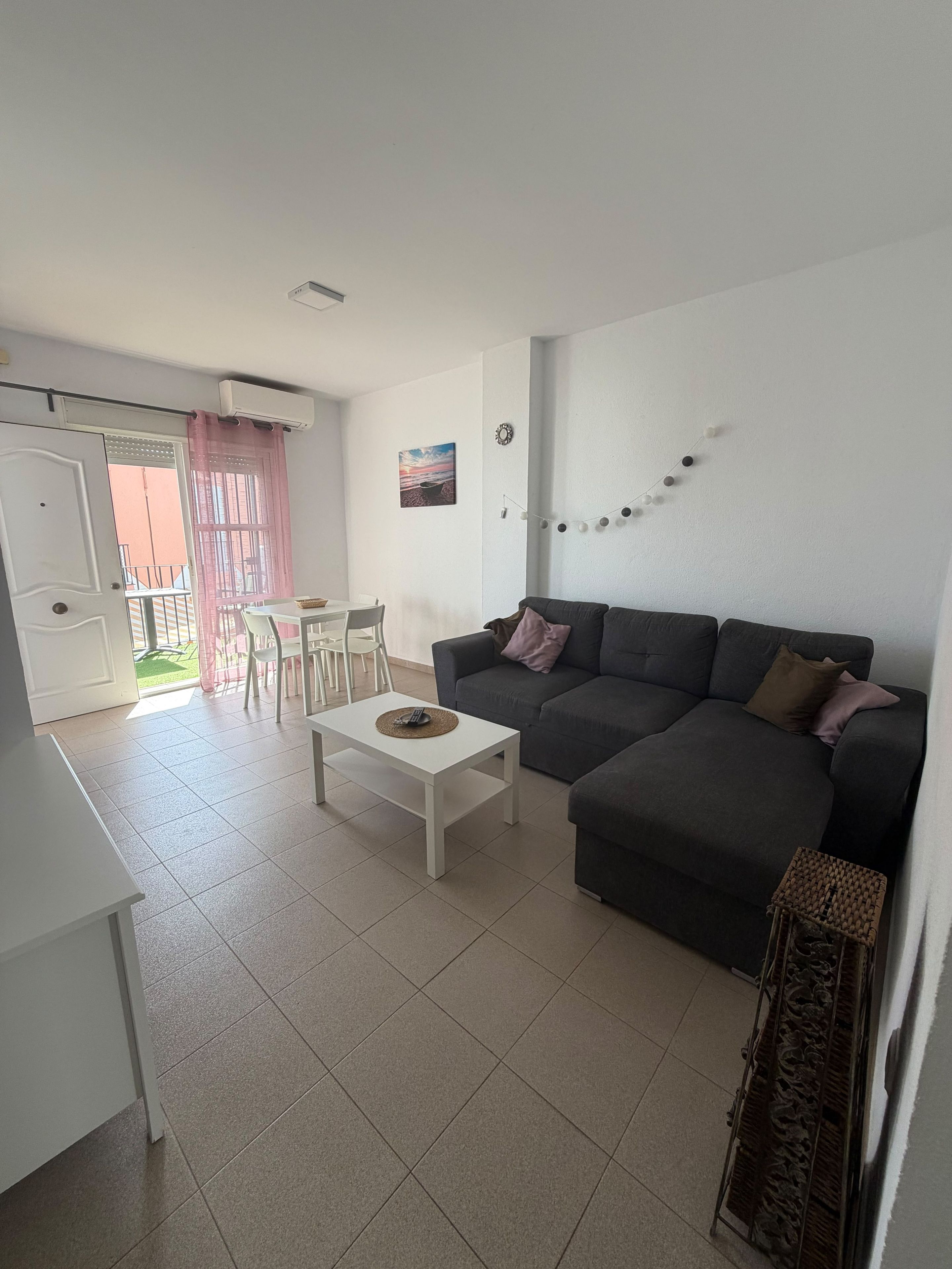 A living room with a sofa, a coffee table, and a dining area with chairs.