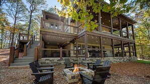 A multi-level wooden cabin with outdoor seating and a fire pit.