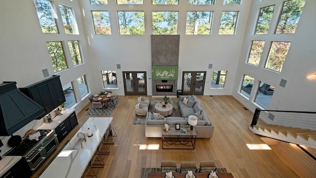 A spacious living area with a fireplace, large windows, and a modern kitchen.