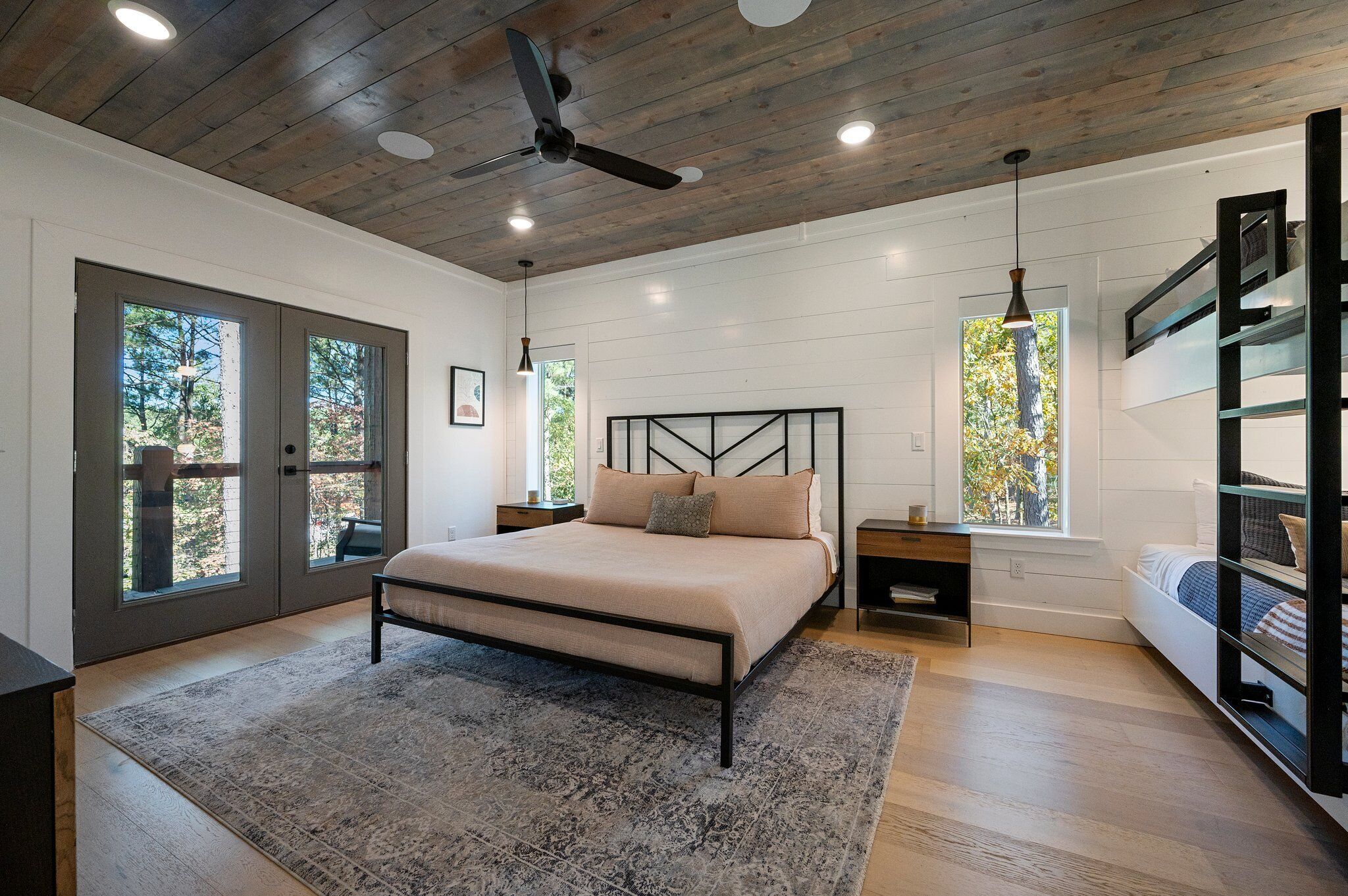 A bedroom with a large bed, a ceiling fan, and a view of the outdoors through a door.