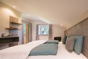 Een slaapkamer met een bed, een raam, een plank met gewei en een hoofdeinde.