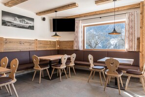 Restaurante com móveis de madeira, uma grande janela com vista e uma televisão montada na parede.