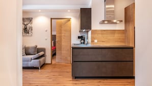 A modern kitchen with a wooden countertop, a built-in stove, and a grey sofa in the adjacent living area. - Apartment "Balbeinhof Apt Hirsch" with Mountain View, Balcony & Wi-Fi (Luson)