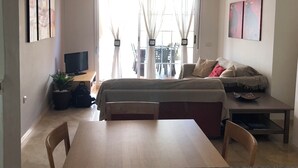 Una habitación moderna y luminosa con una cama, un televisor, una mesa de comedor y un sofá.