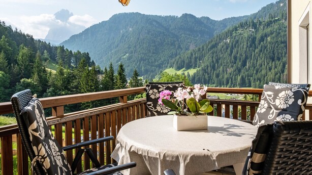 A balcony with a table, chairs, and a flower vase. - Holiday Apartment "Salman" with Mountain View, Balcony & Wi-Fi (Ortisei)