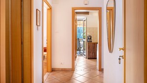 A hallway with wooden doors, a tiled floor, and a view into a room with a chair and a table. - Holiday Apartment "Salman" with Mountain View, Balcony & Wi-Fi (Ortisei)