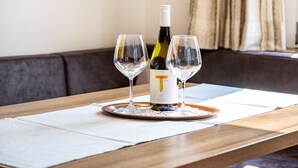 A wooden table with a bottle and two glasses on a coaster. - Holiday Apartment "Salman" with Mountain View, Balcony & Wi-Fi (Ortisei)