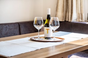 A wooden table with a bottle and two glasses on a coaster.