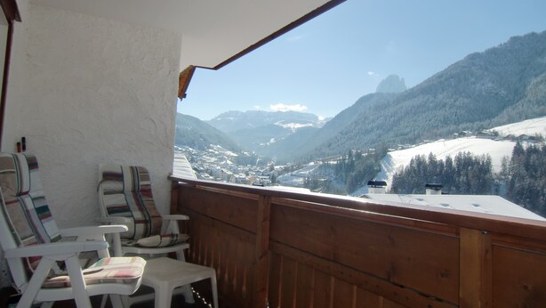 Un balcon avec des chaises donnant sur un paysage montagneux enneigé.
