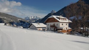 Un village de montagne enneigé, avec des maisons et un sommet montagneux imposant en arrière-plan.