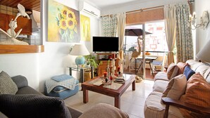 A living room with a sofa, coffee table, TV, and a dining area with chairs and a table.