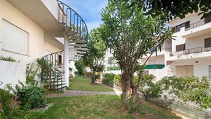 A residential building with a spiral staircase, a small garden, and a pathway.